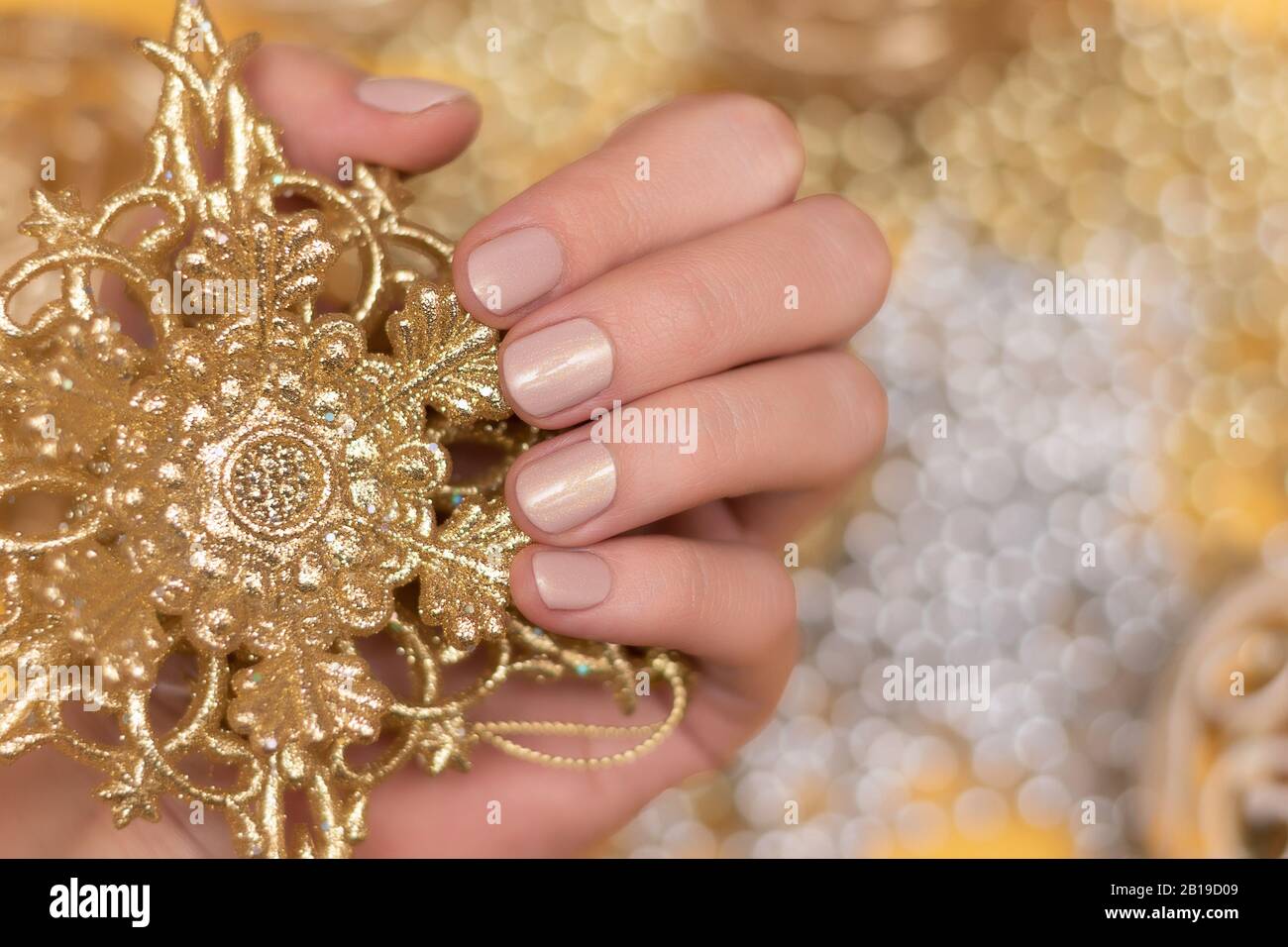 Female hand with nude glitter nail design. Stock Photo