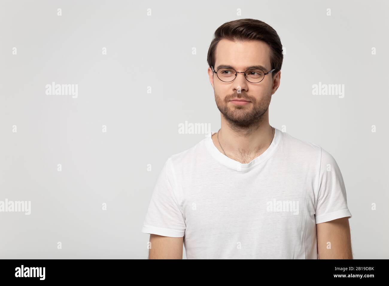 Thoughtful young confident man wearing eyeglasses standing aside copy space. Stock Photo