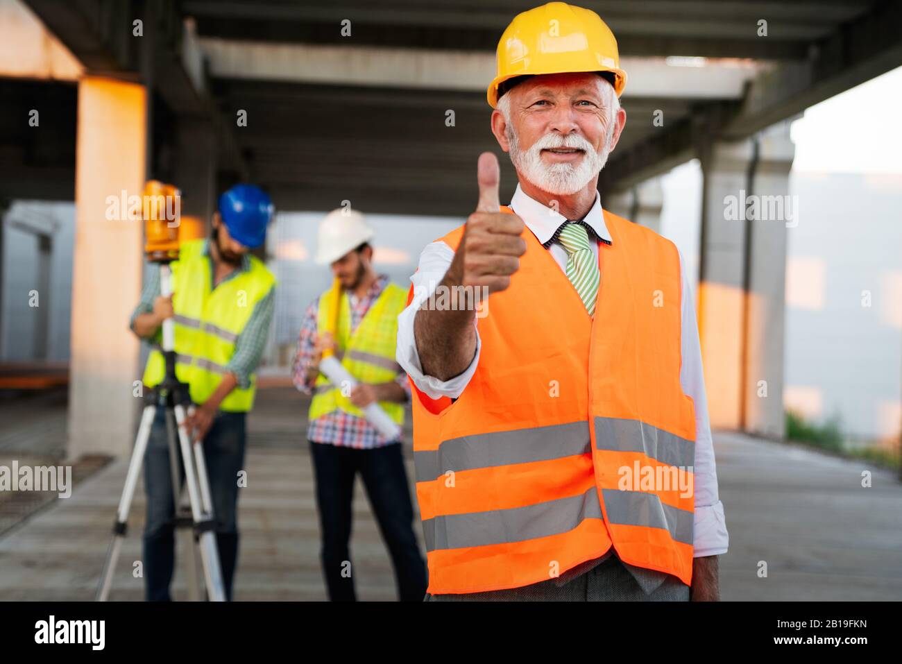 Two satisfied engineers talking at building site with construction structure in background Stock Photo