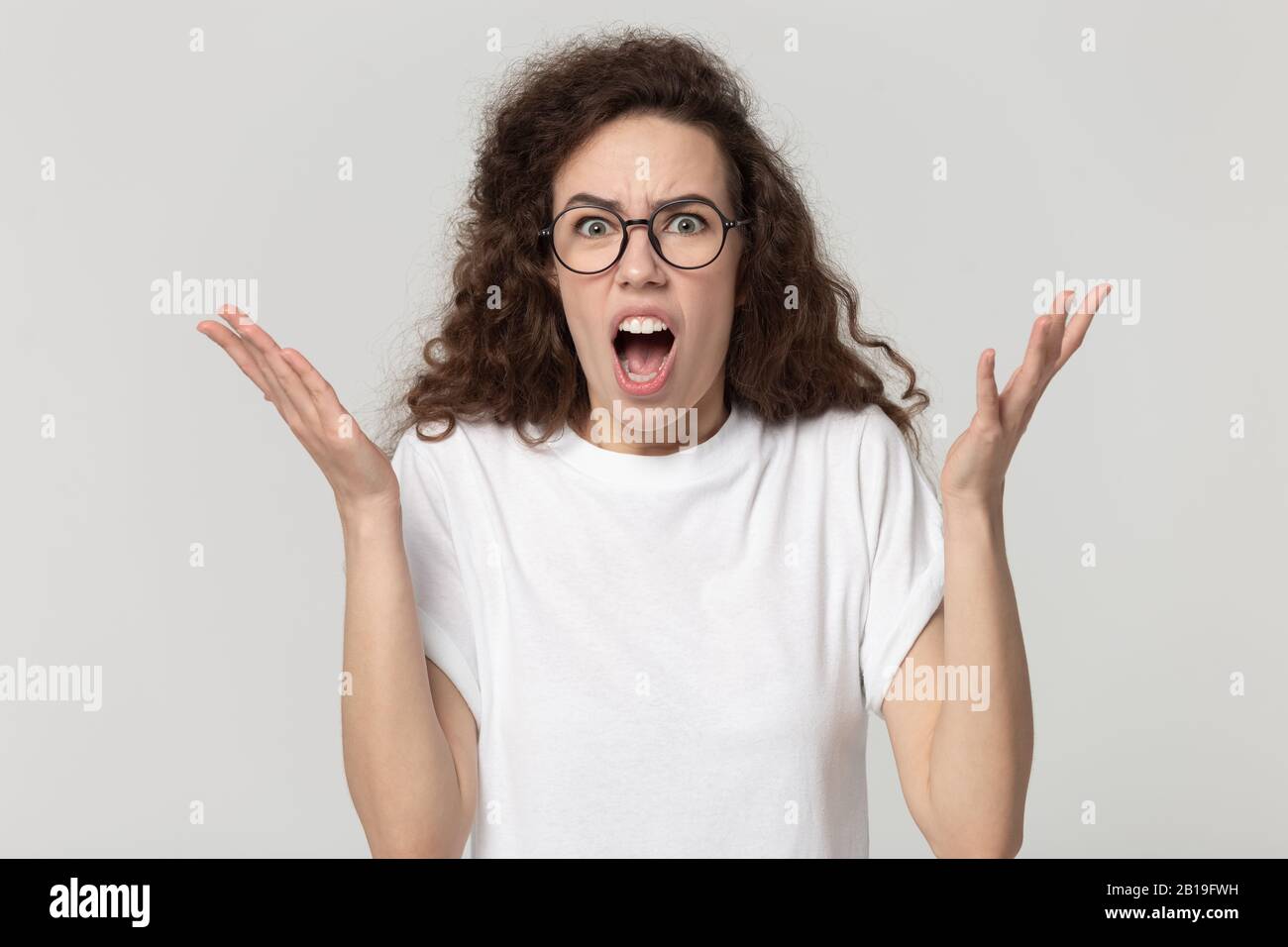 Millennial woman in eyeglasses feeling anger, annoyed by bad news. Stock Photo