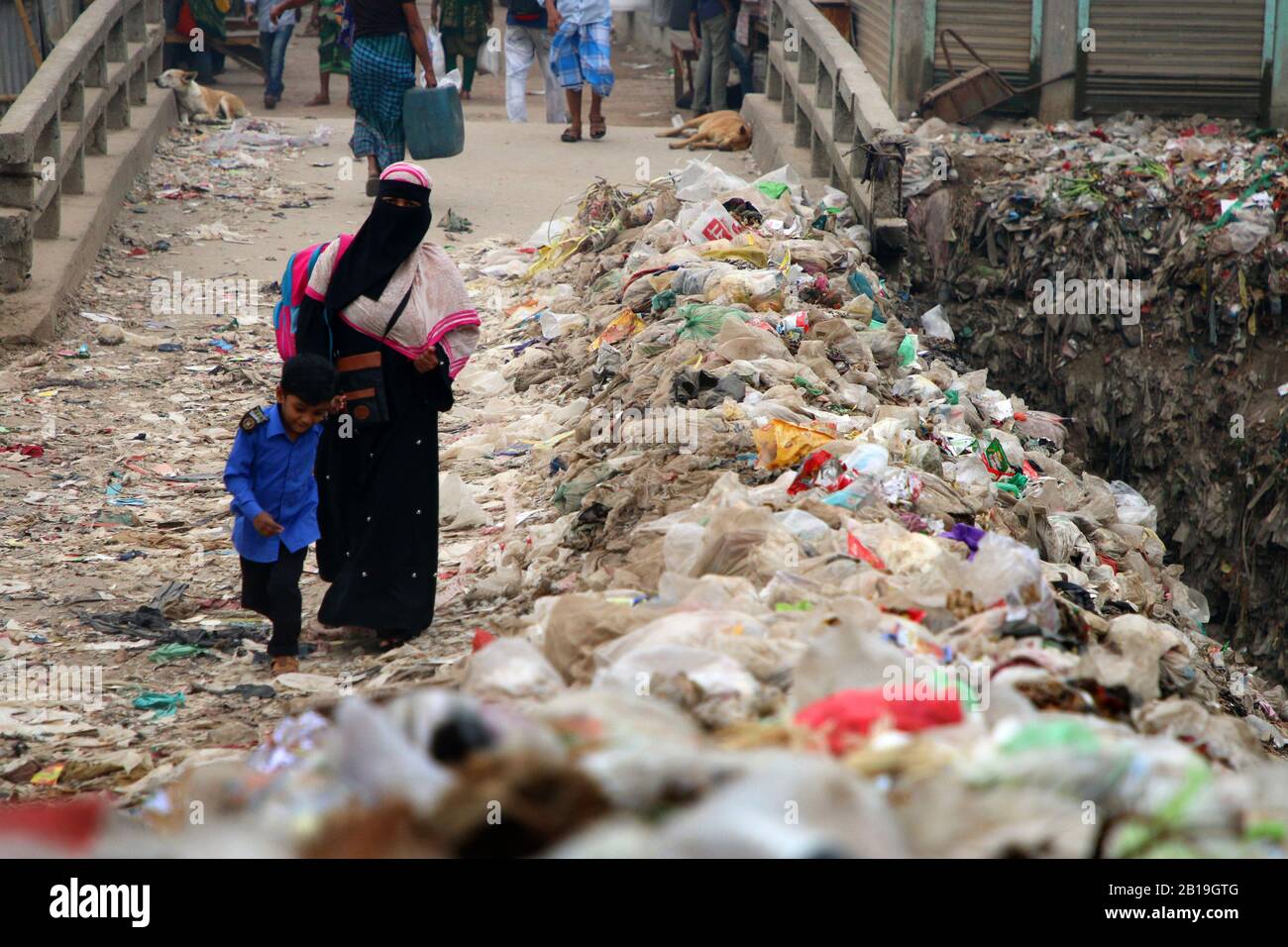 Dhaka, Bangladesh. 25th Feb, 2020. A woman with a kid walk past dumped