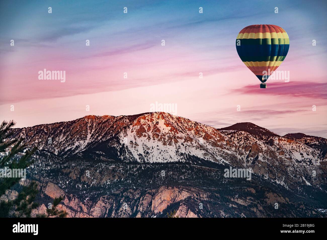 Hot air balloon flying against a snowed mountains in the Pyrenees in a adventure sports tourism activiry. Nature landscape background.Empty copy space Stock Photo