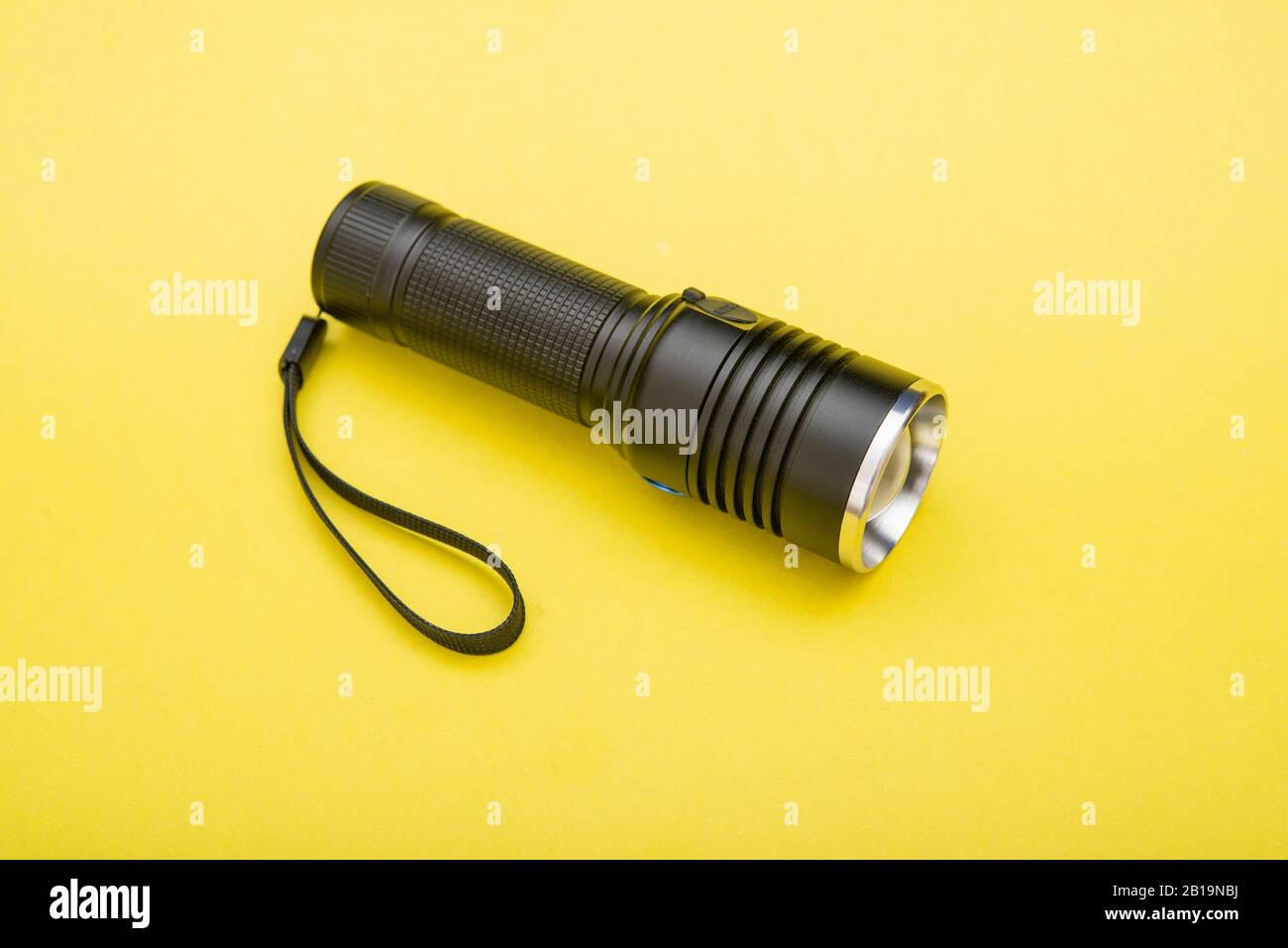 Battery powered flashlight on a yellow background with copy space Stock Photo