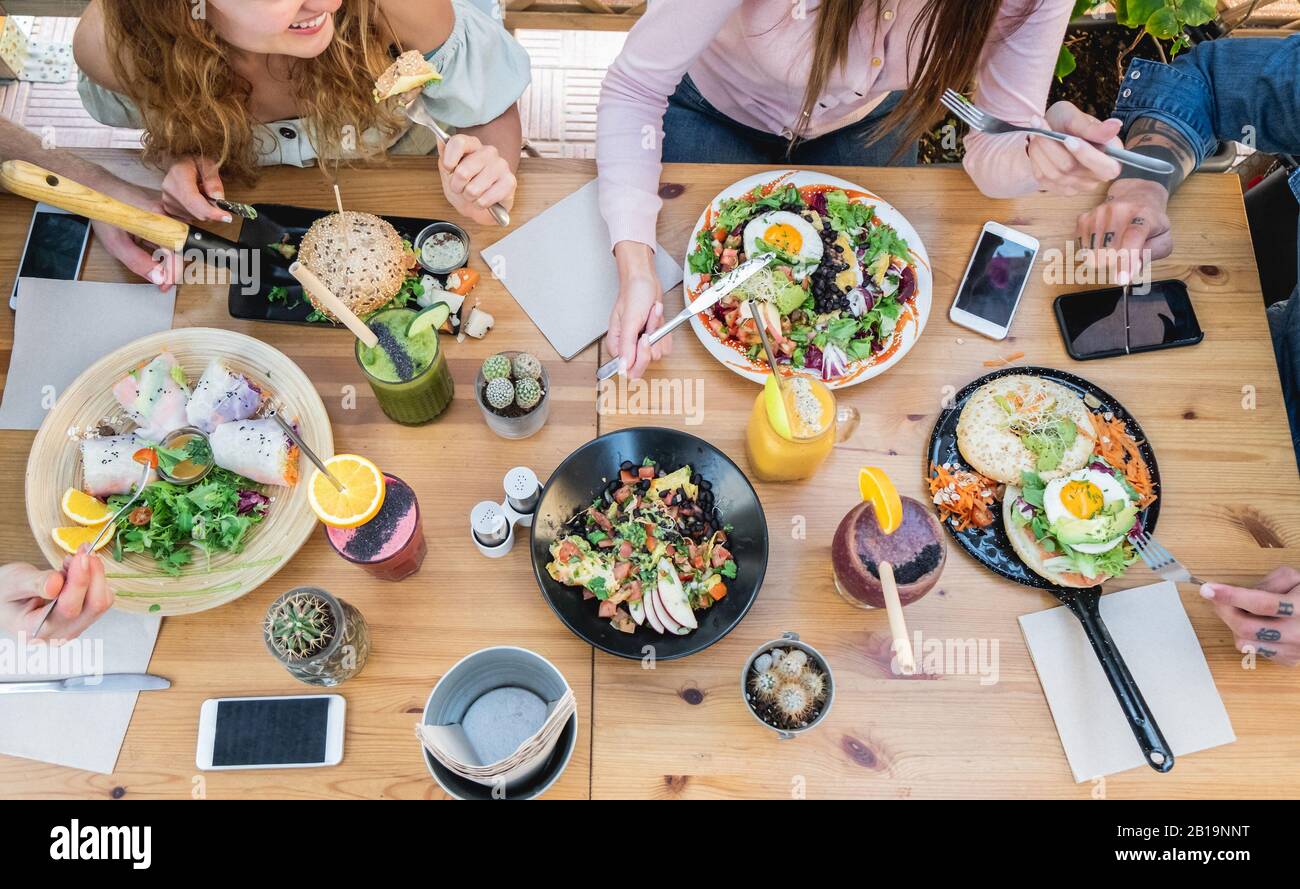 Top view of young people eating brunch and drinking smoothie bowl at  vintage bar - Students having a lunch and chatting in trendy restaurant - Food t Stock Photo