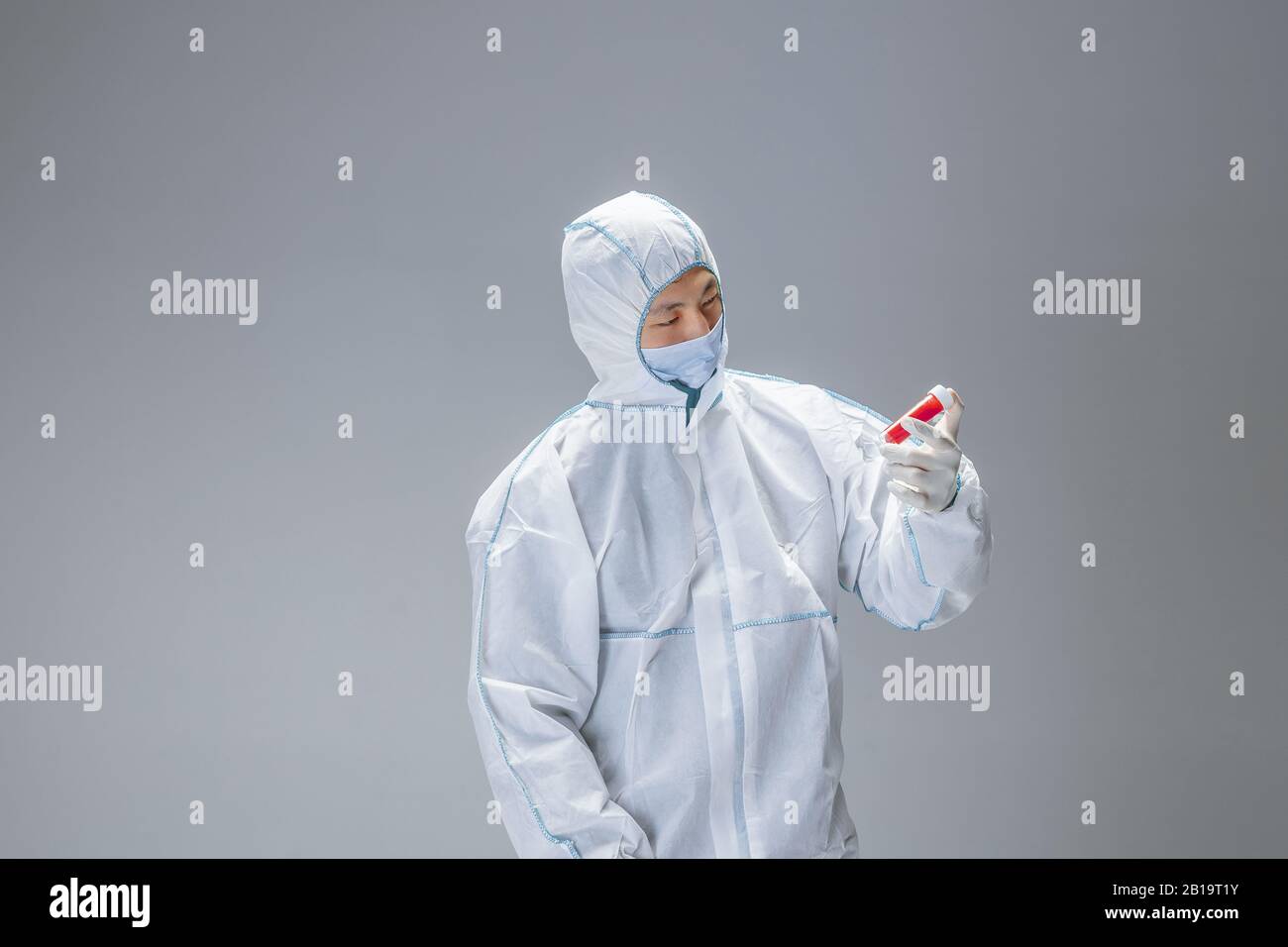 Dangerous. Medic in white hazmat protective suit checking and scanning ...