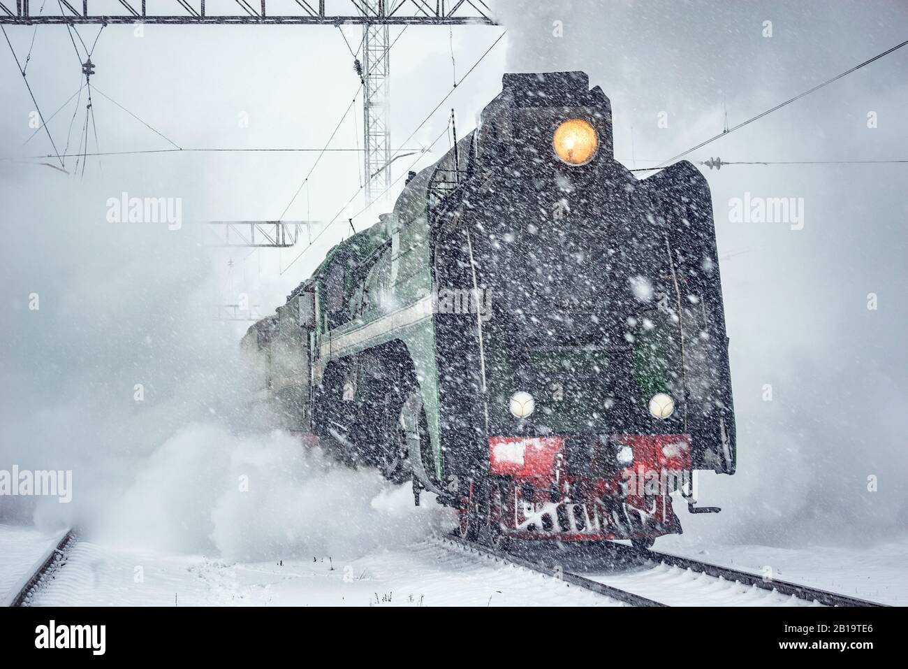 Retro steam train departs from the railway station at winter snowy time ...
