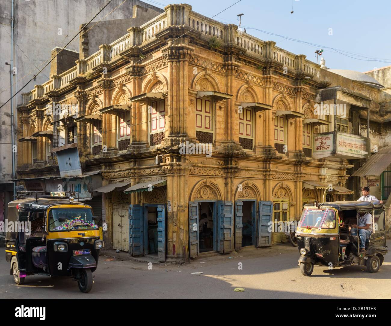 Junagadh, Gujarat, India - December 2018: A beautiful yellow building with arcaded windows and vintage wooden doors in the old market area. Stock Photo