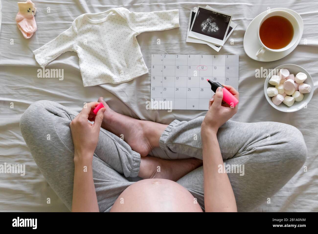 Top vew of expecting pregnant woman notes date of birth on the calendar, pregnancy and birth concept Stock Photo