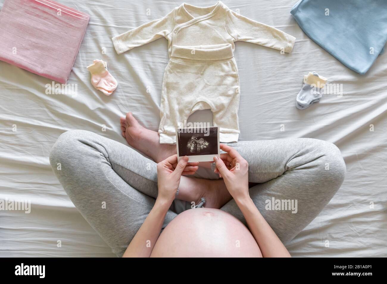 Top view of expecting pregnant woman in bed looking at ultrasound scans, boy or girl, pregnancy and birth concept Stock Photo