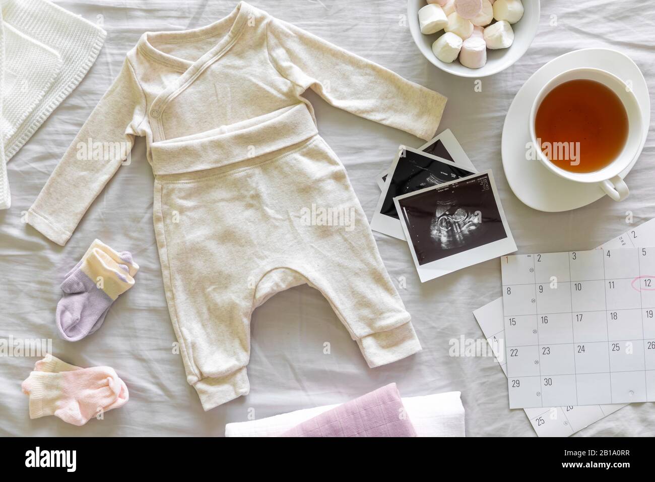 Baby clothes, calendar with the expected date of birth of baby, tea and ultrasound scan, pregnancy and birth concept Stock Photo