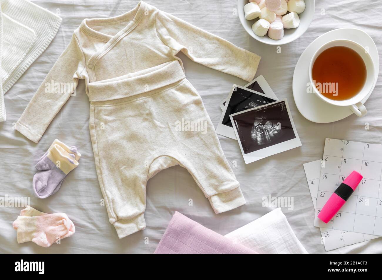 Baby clothes, calendar with the expected date of birth of baby, tea and ultrasound scan, pregnancy and birth concept Stock Photo