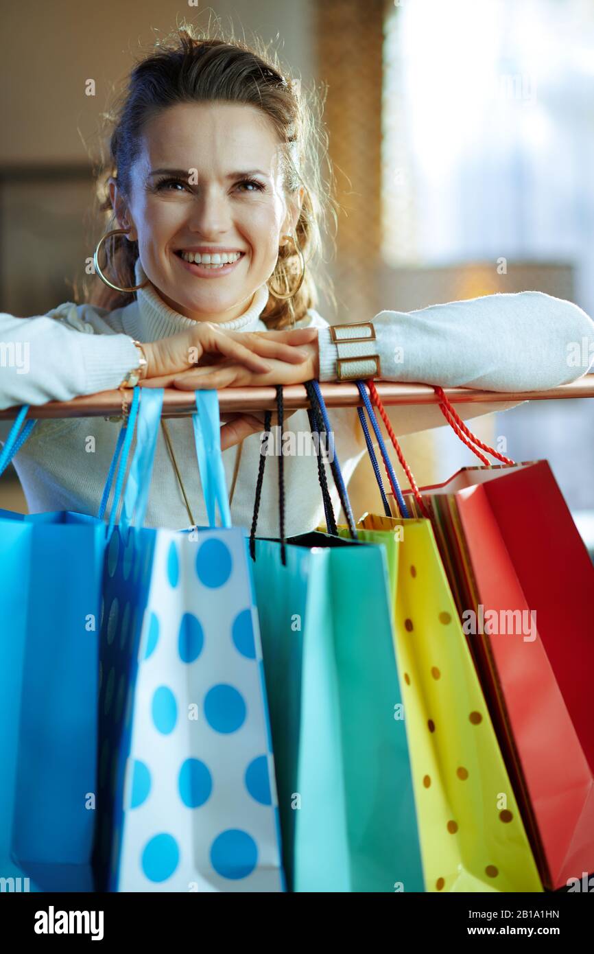 happy trendy 40 years old woman in white sweater and skirt near