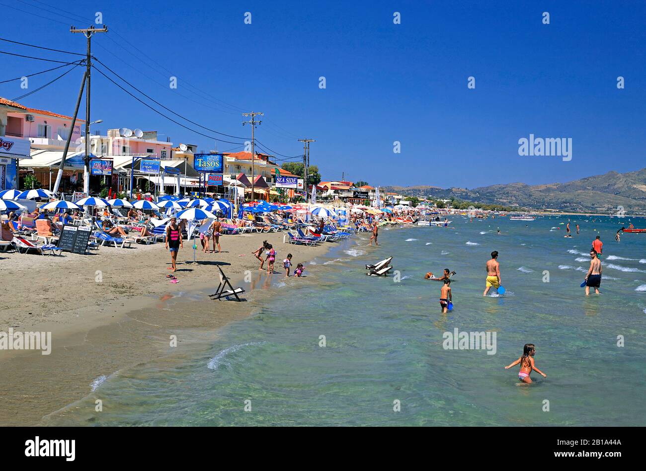 Urlauber am Sandstrand von Laganas, touristischer Ort auf der Insel Zakynthos, Griechenland | People at the beach of Laganas, Zakynthos island, Greece Stock Photo