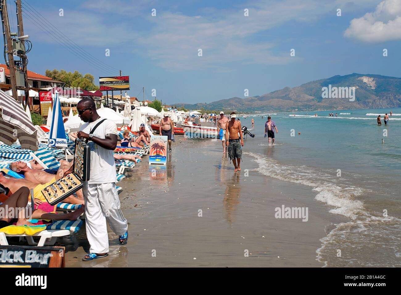 Dark-skinned immigrant sells watches at the beach of Laganas, Zakynthos Stock Photo