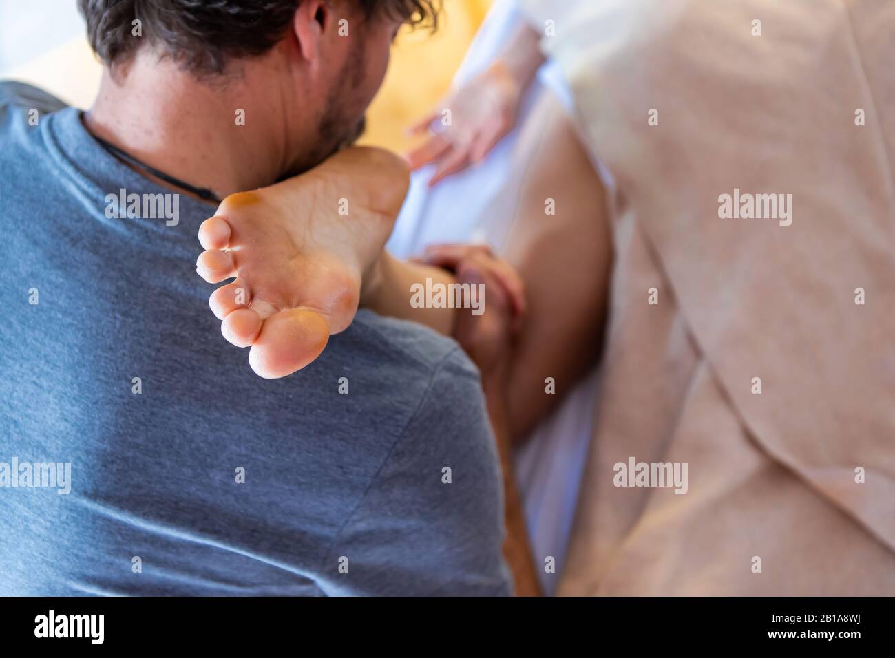 A professional masseur doing leg massage in a cosy home environment. Body care. Spa body massage treatment. Woman having massage Stock Photo