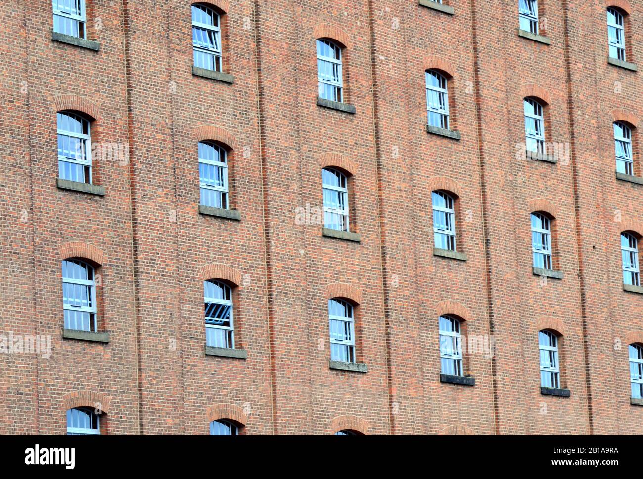 Pattern of the windows and brick wall of a former warehouse in city centre Manchester, United Kingdom Stock Photo
