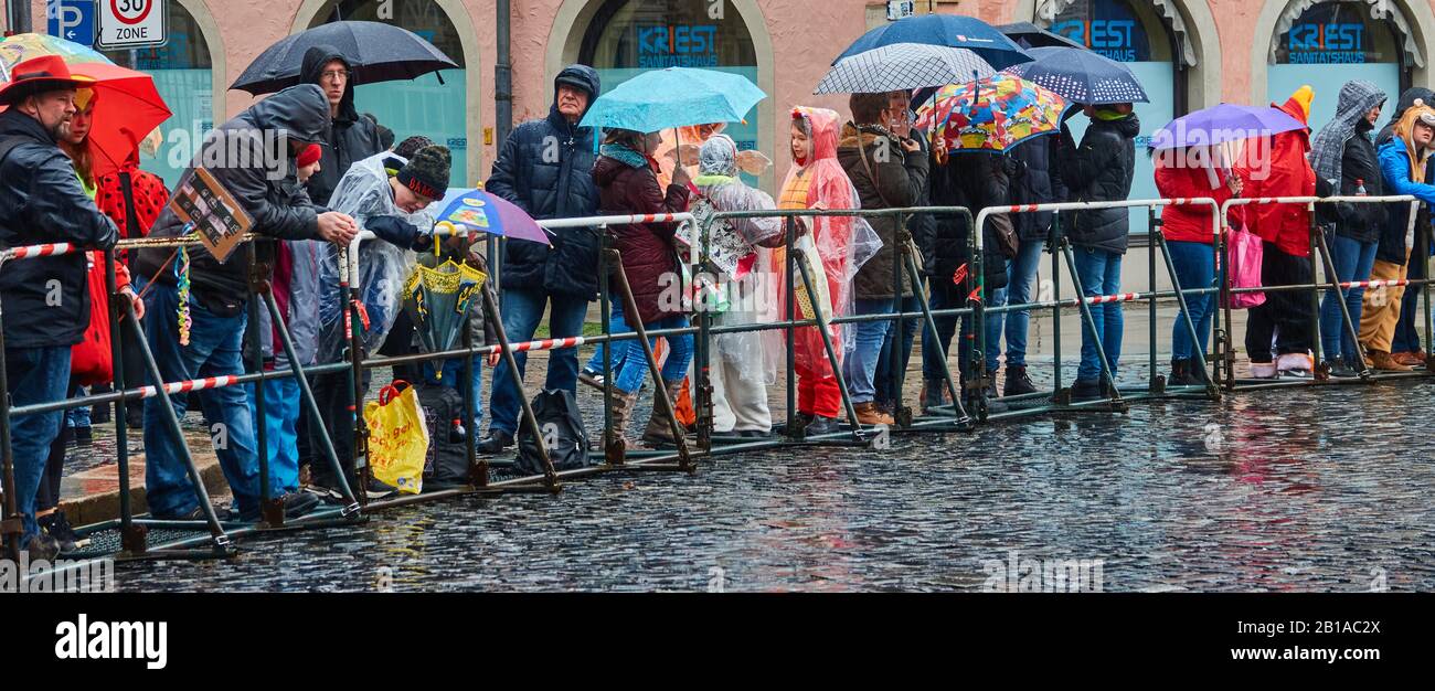 Braunschweig, Germany, February 23., 2020: Spectators with rain protection, rain jackets and umbrellas wait behind the barrier in the rain for the car Stock Photo