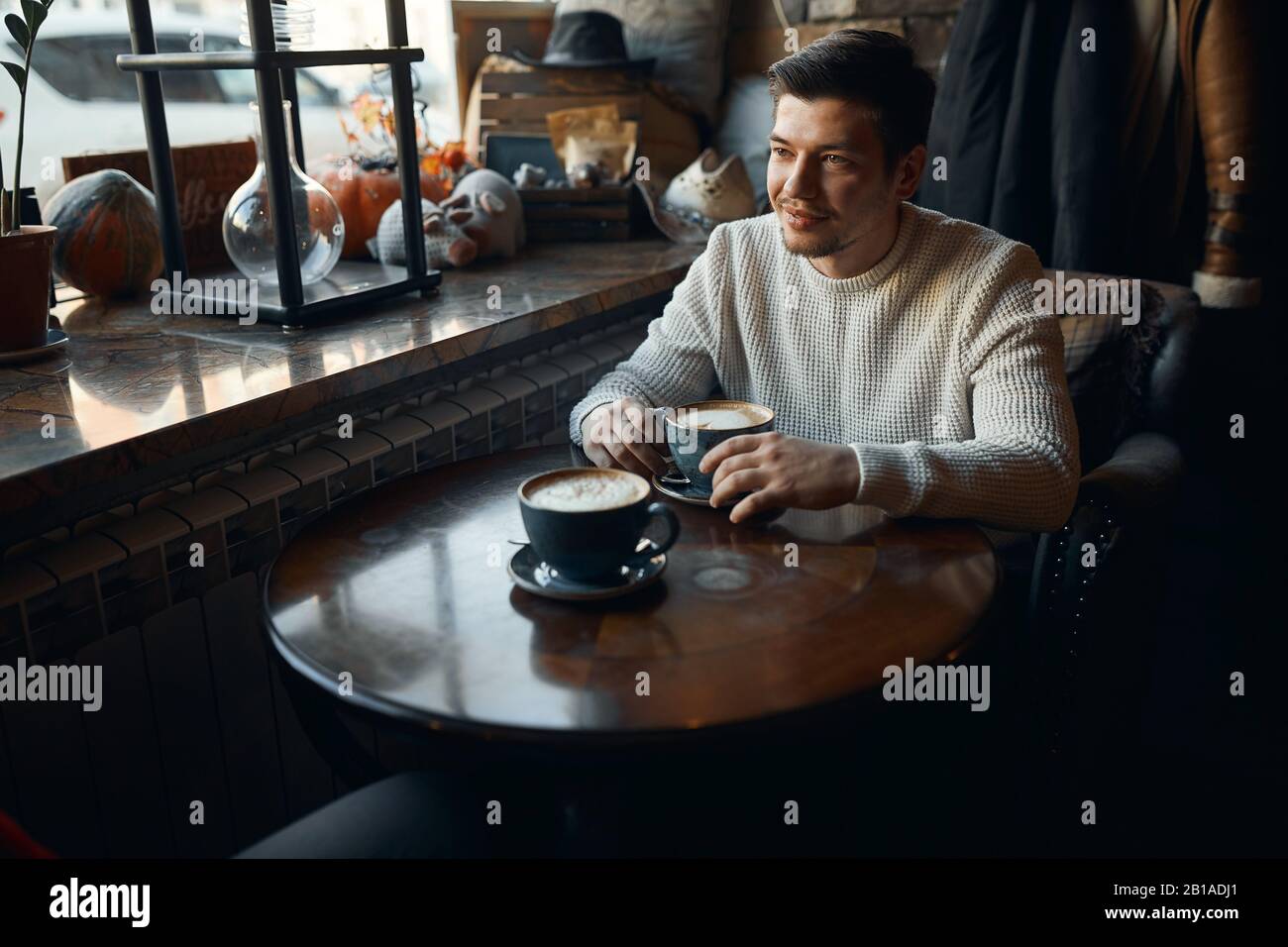Young handsome thoughtful pensive man with a cup of coffee waiting for his girlfriend, close up photo, beauty, love, date Stock Photo