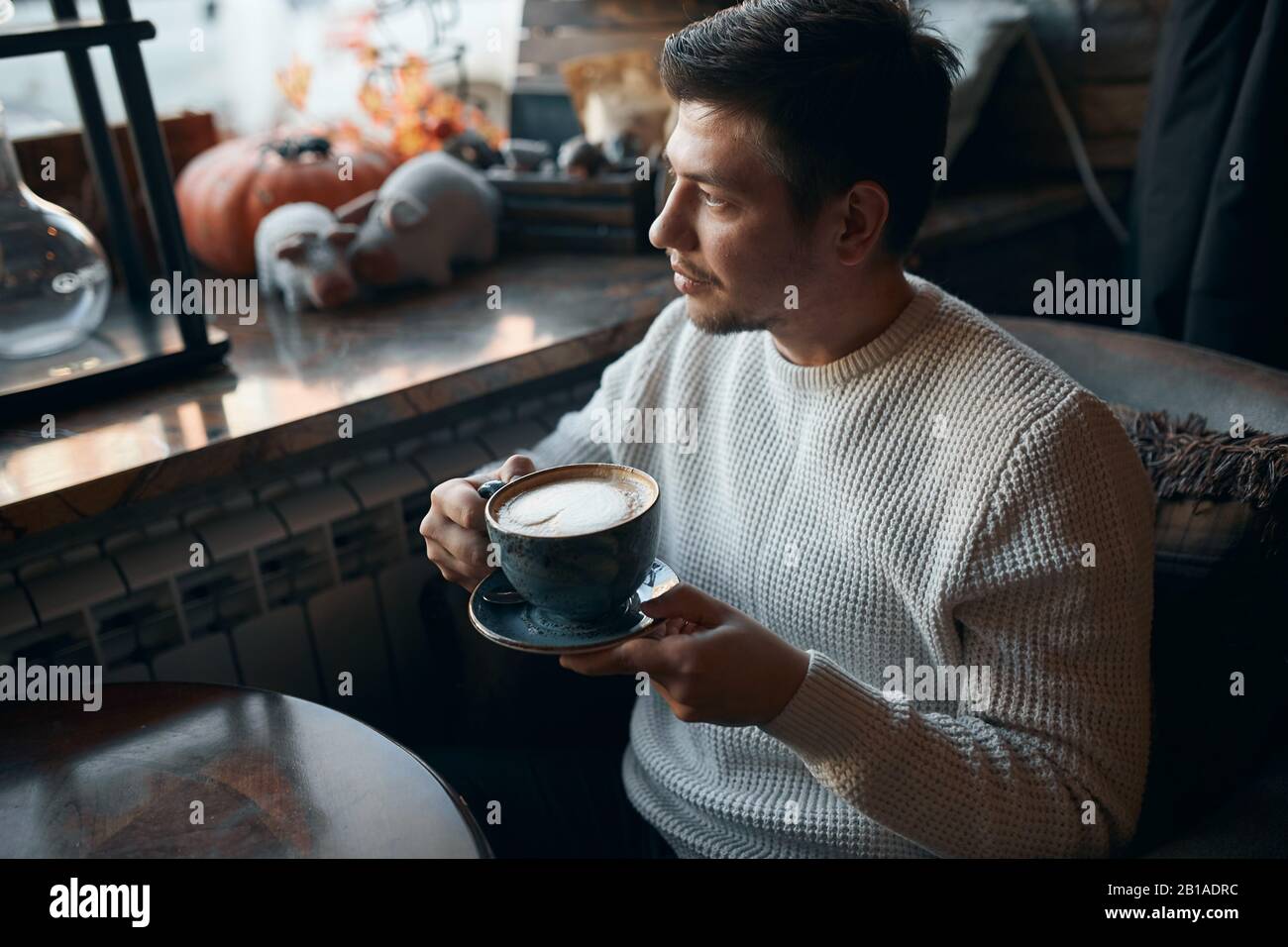 young pleasant guy having coffee break after work, enjoyment concept. close up side view photo. free time, lifestyle, leisure Stock Photo