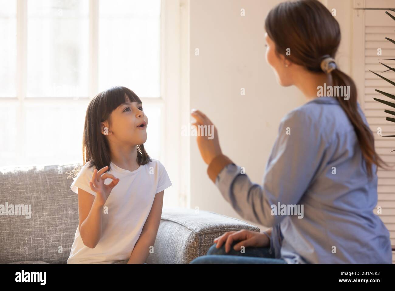 Mom and daughter practice sign language at home Stock Photo