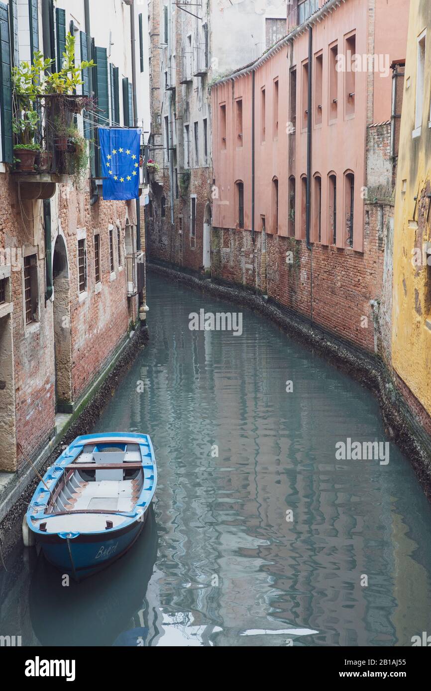 An EU flag flies from a building beside a canal with no people in Venice, Italy Stock Photo