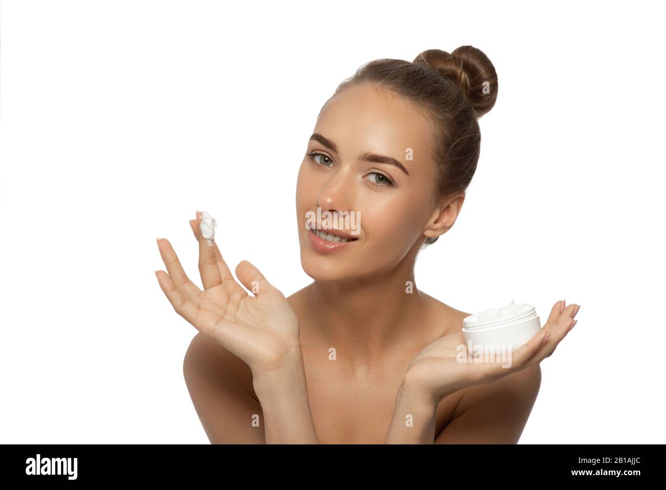 Beautiful young woman with facial cream in her hands isolated on white