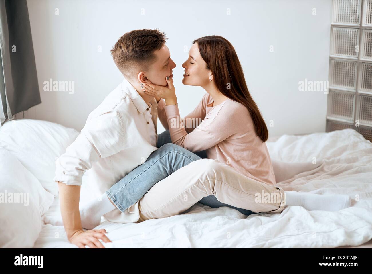 young lovely woman congratulating her husband with birthdaym girl touching her boyfriend's cheeks and going to kiss him Stock Photo