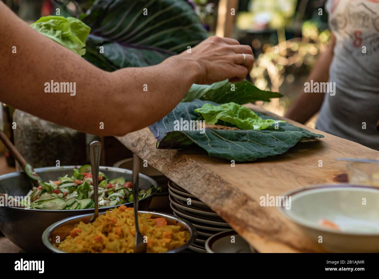 A closeup and selective focus view as organic food is served on large green collard leaves during a festival promoting healthy lifestyle and earth Stock Photo