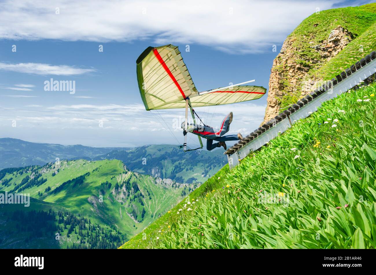 Hang glider pilots runs from steep slope high in the mountains. Diedamskopf, Austria. Extreme airborne sport. Stock Photo