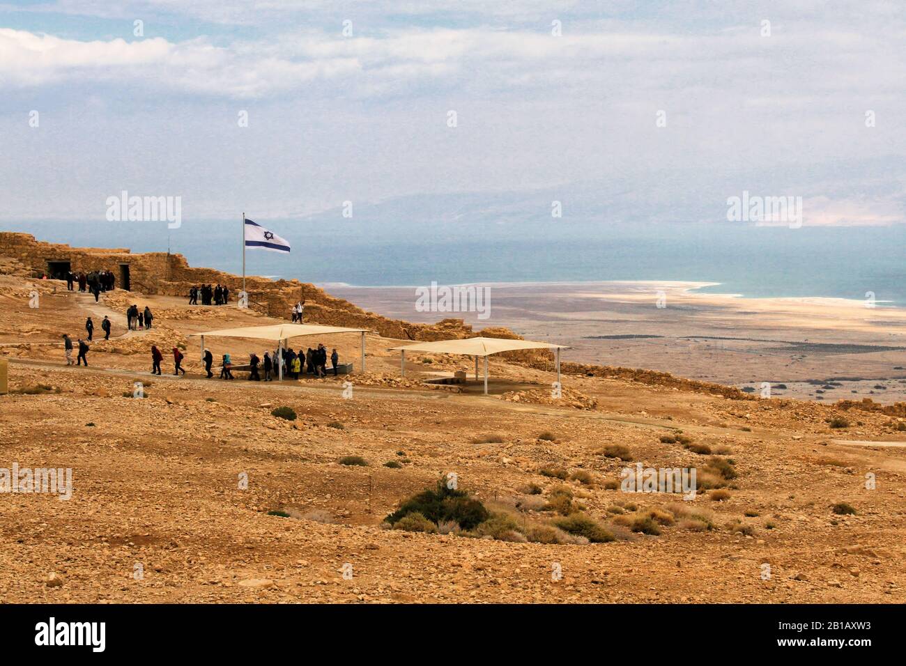 People walk along the top of Masada's plateau in Israel with the Dead Sea in the background. Stock Photo