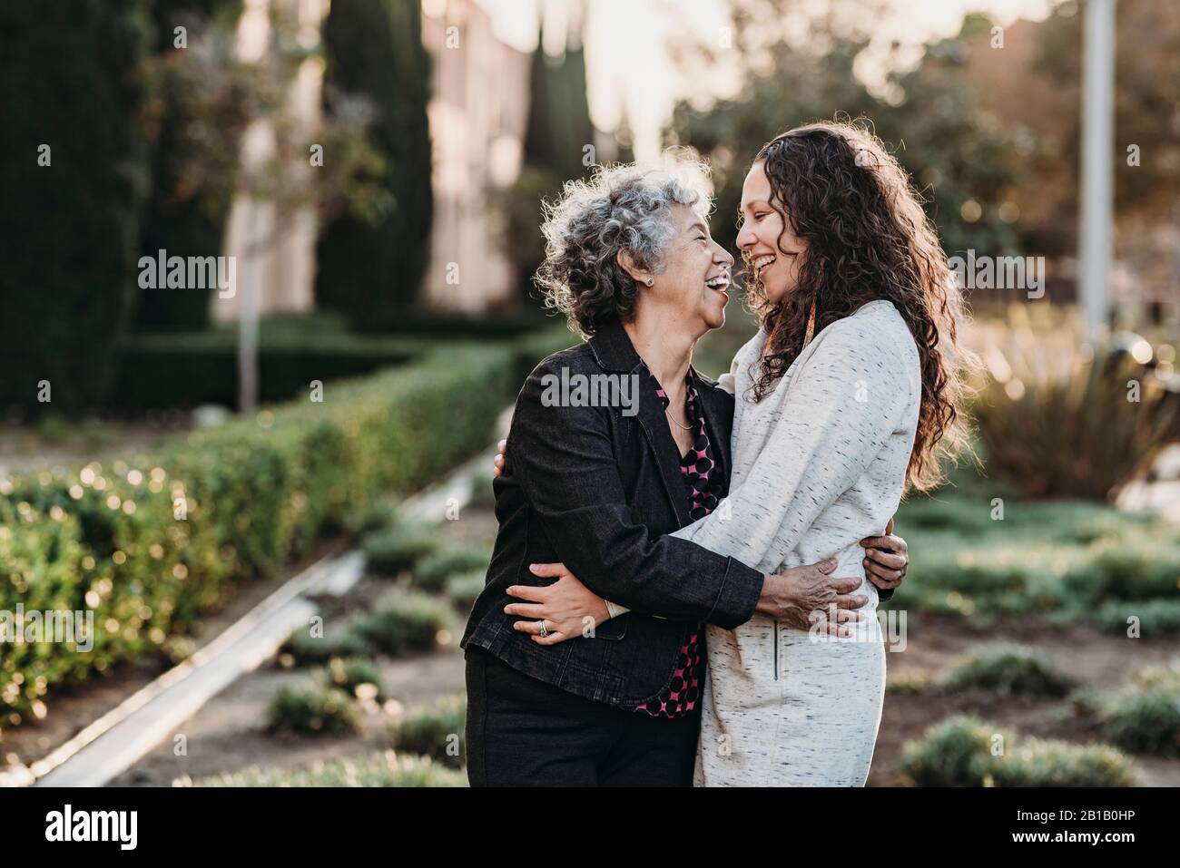 Active senior grandmother and adult daughter hugging outside Stock Photo