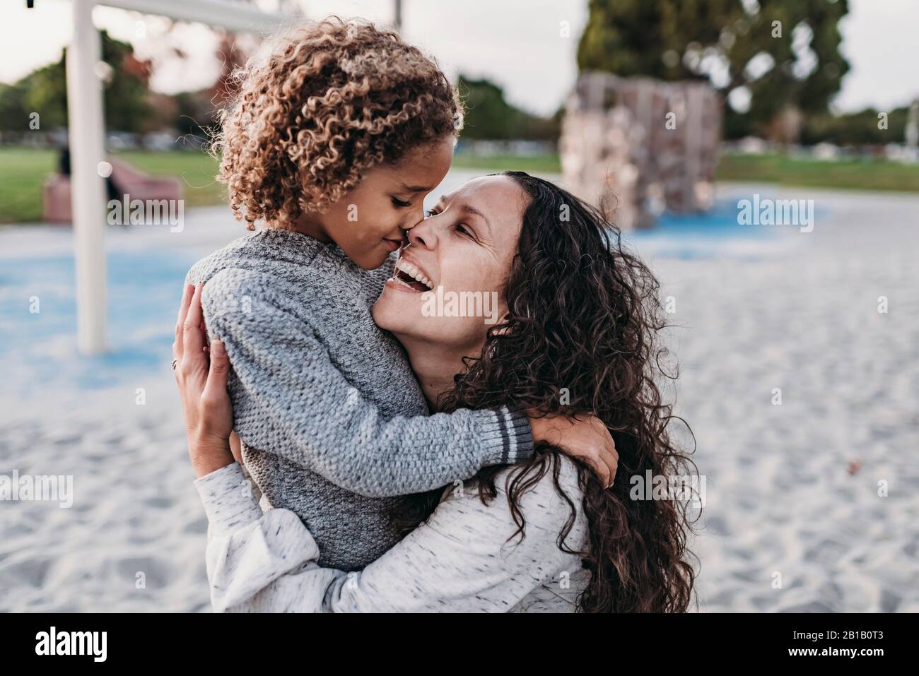 Close up of happy mother and son embracing closely on playground Stock Photo
