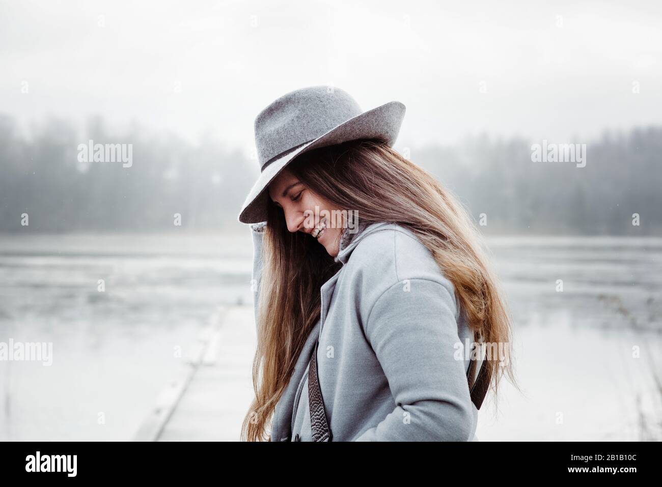 profile of a woman with long brown hair and a hat on laughing smiling Stock Photo