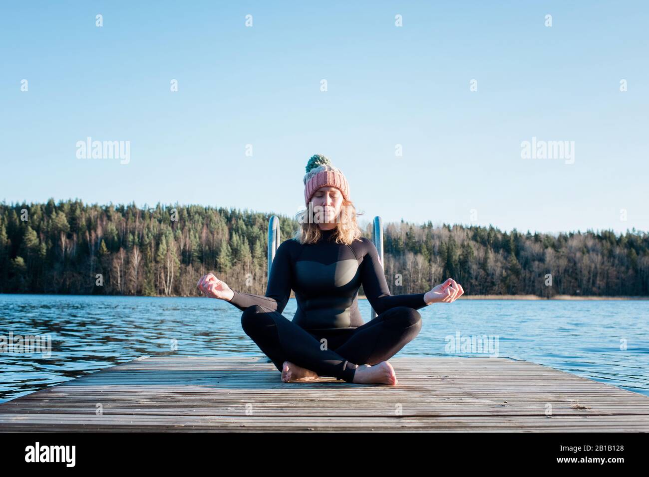 woman meditating in a wetsuit at the beach before cold water swimming Stock Photo