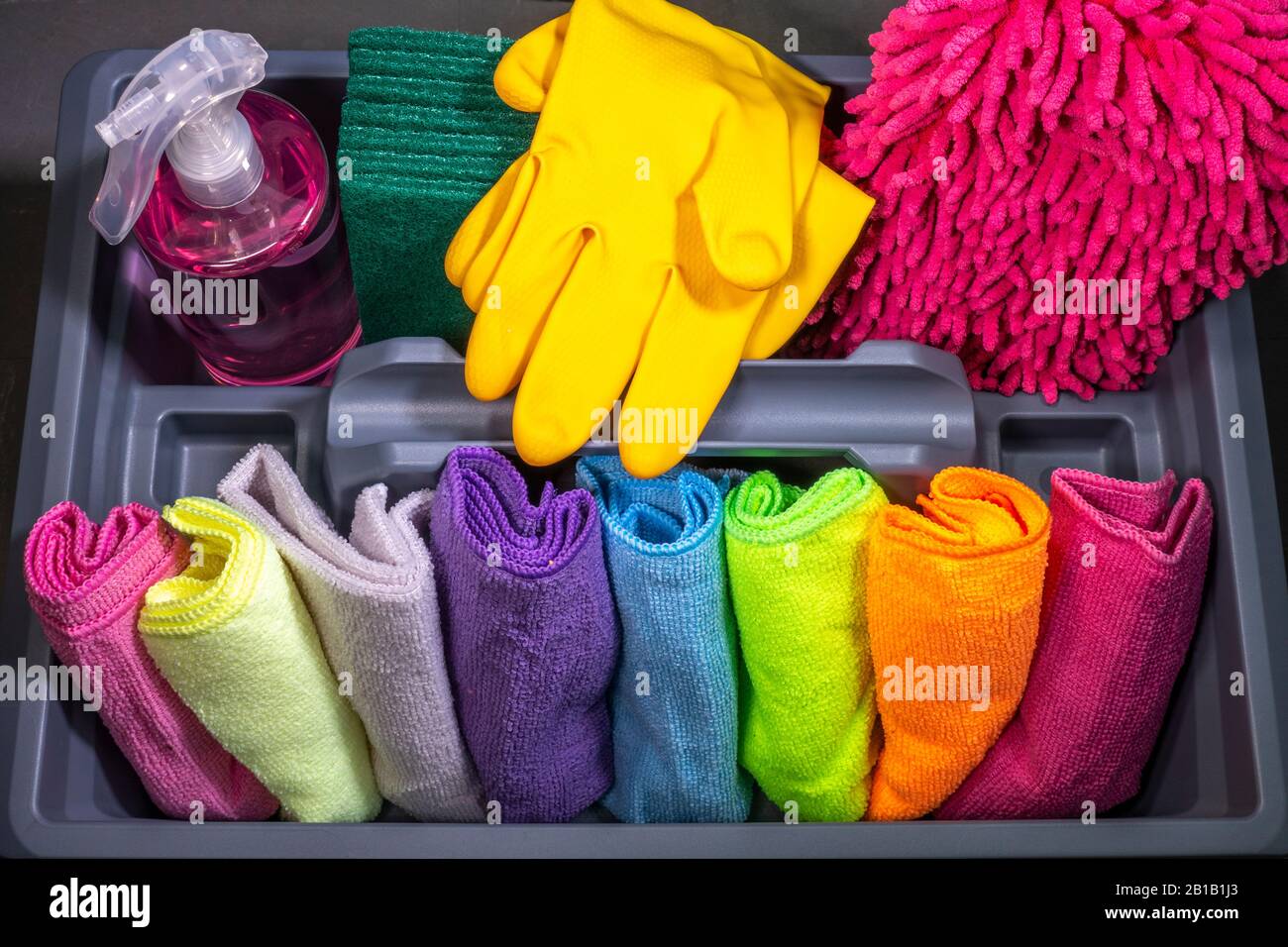 Close POV overhead shot of household cleaning materials of various bright colours in a plastic box / container. Stock Photo