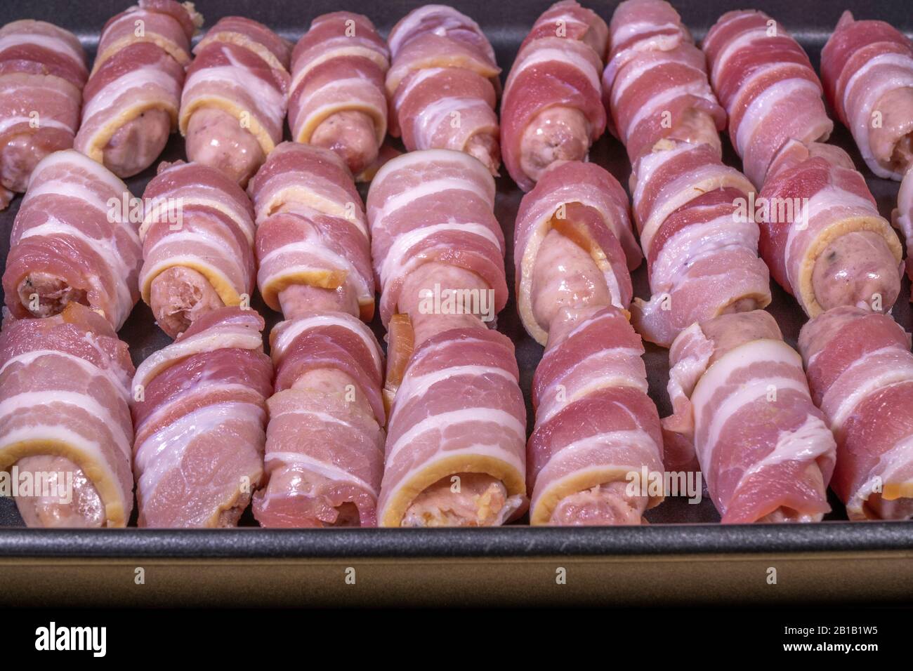 Raw sausages wrapped in bacon (sometimes called pigs in a blanket), in