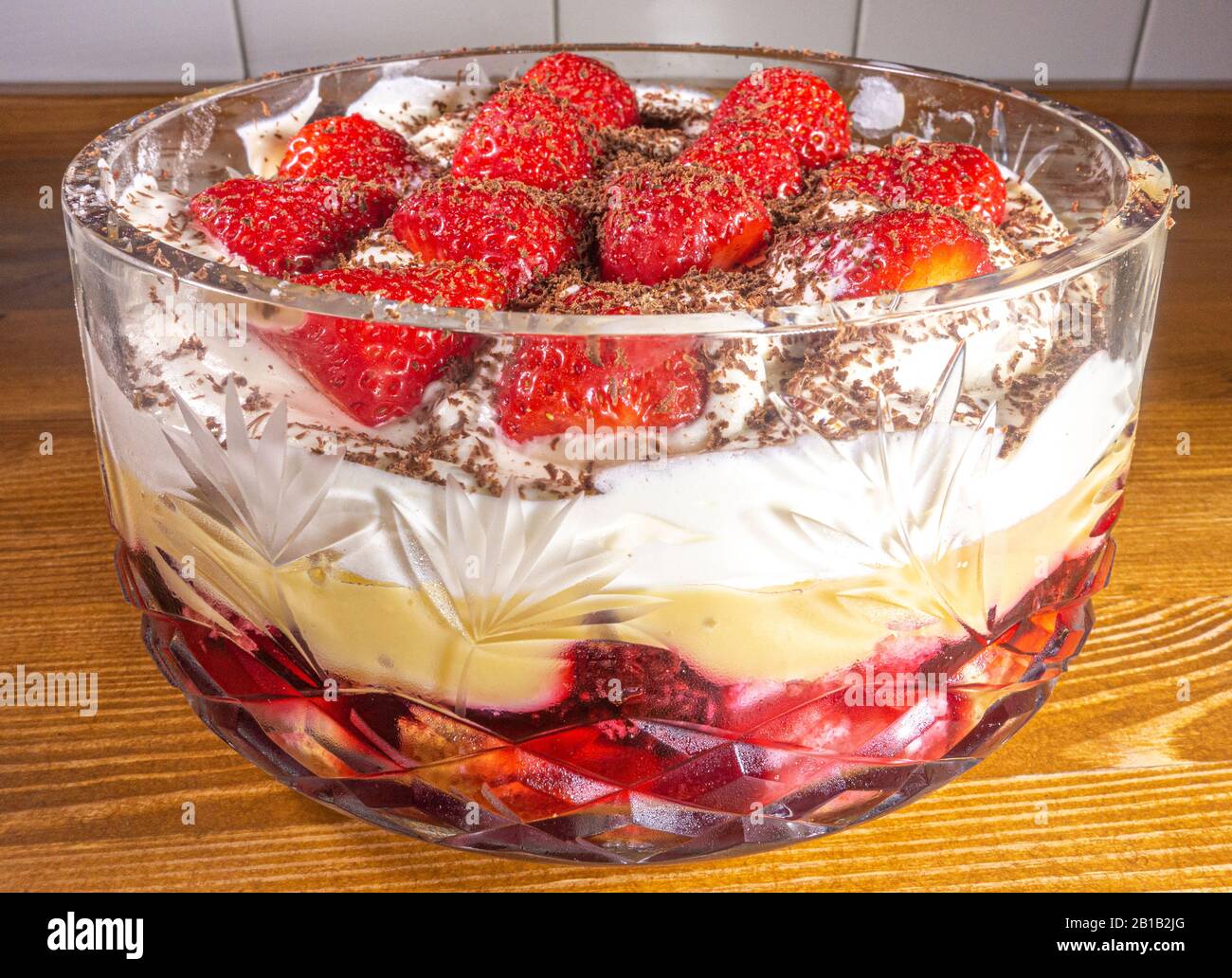 Fresh fruit trifle topped with strawberries in a decorative, crystal glass bowl. Stock Photo