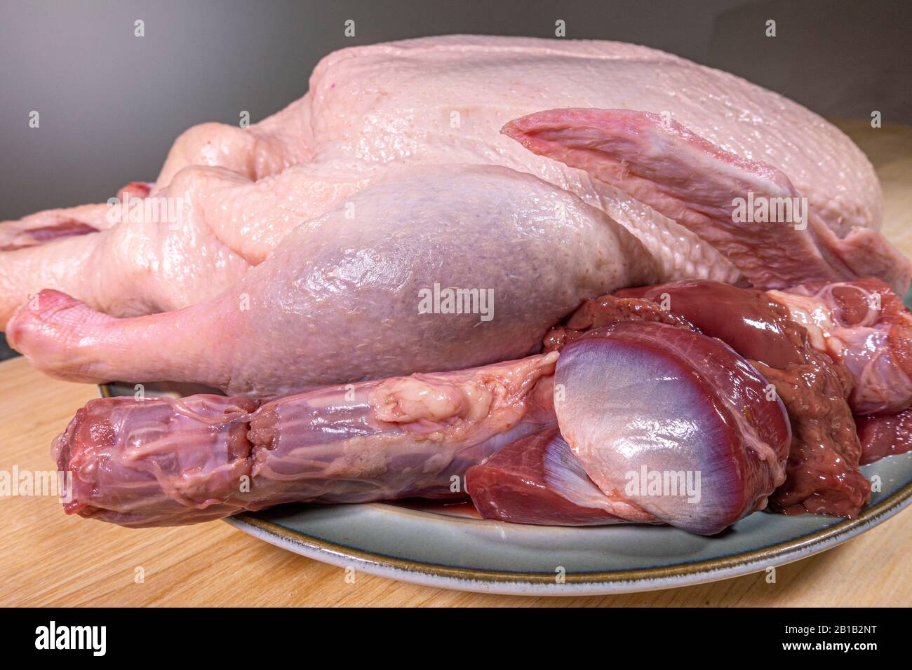 A whole raw / uncooked duck with giblets resting on a plate prior to cooking. Stock Photo