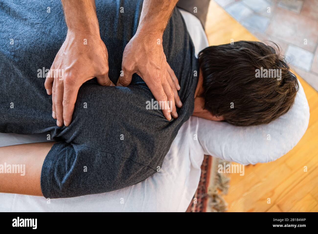 Therapist doing back massaging to strong sportsman. A male patient
