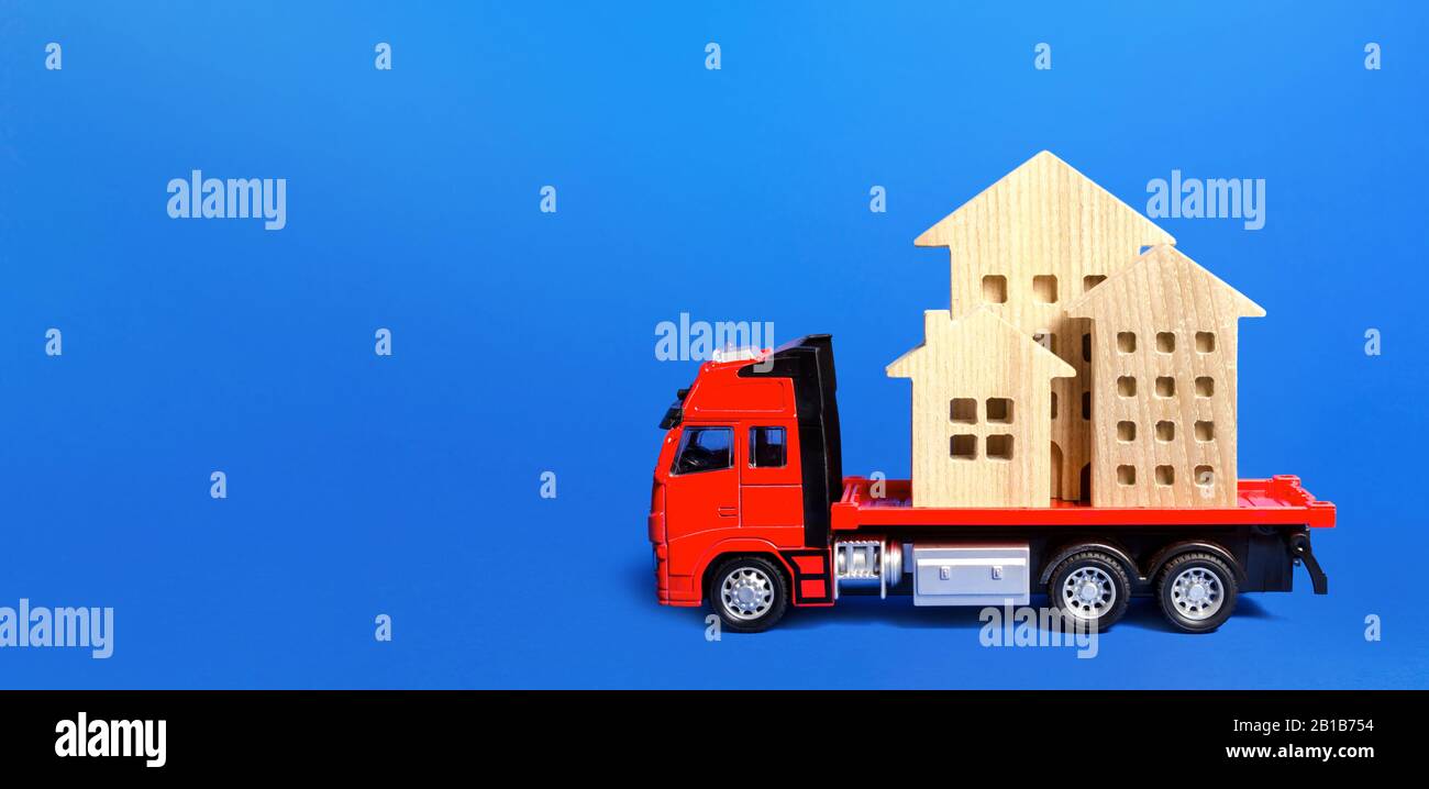 Red freight truck loaded with figure houses. Relocation of buildings and monuments. Cargo transportation, delivery service. A moving company. Infrastr Stock Photo