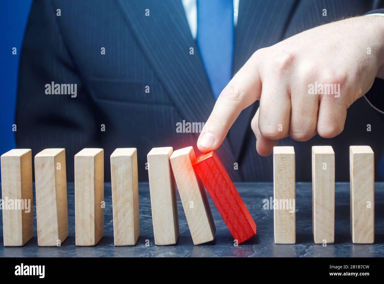 Businessman starts the process of falling dominoes. Correction of errors malfunctions. Implementation of plans. Starting work after stopping. Continua Stock Photo