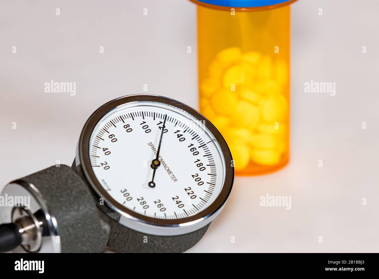 Closeup of blood pressure cuff gauge with normal systolic reading of 120 mmHg. prescription medicine bottle with pills in background Stock Photo