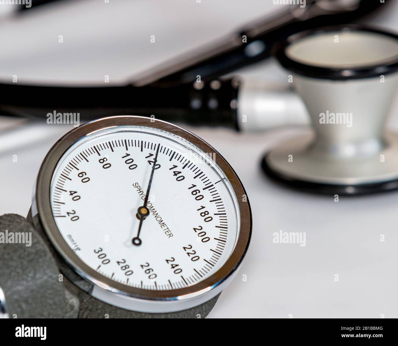 Closeup of blood pressure cuff gauge with normal systolic reading of 120 mmHg. Stethoscope in background. Stock Photo