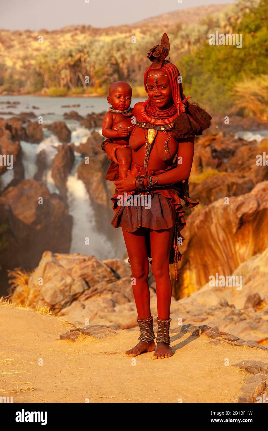 Himba woman sporting his neck full of traditional ornaments and a small ...