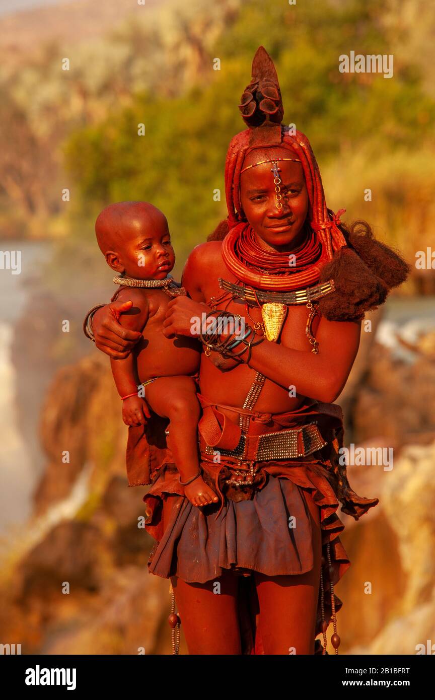 Himba woman sporting his neck full of traditional ornaments and a small ...