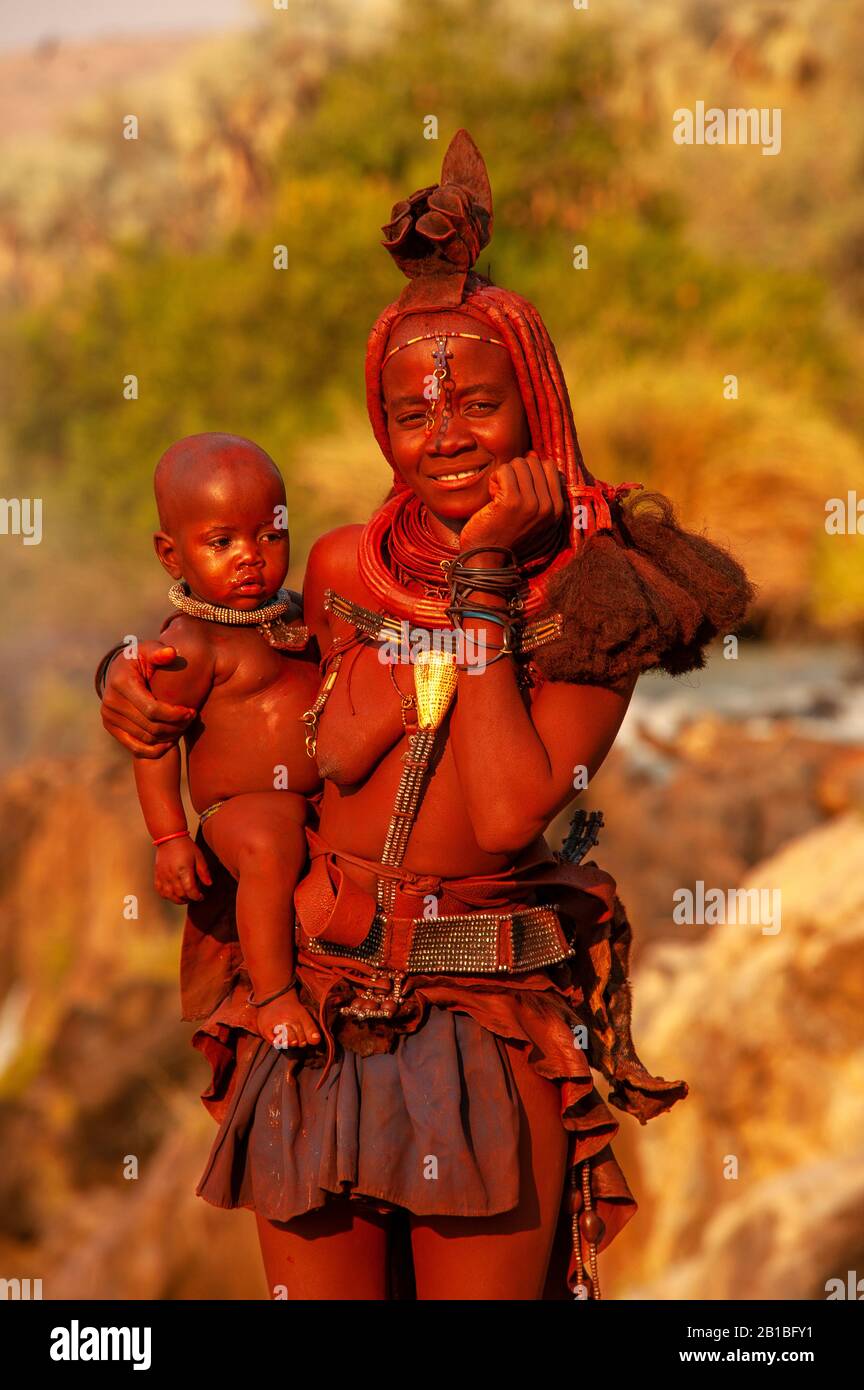 Himba woman sporting his neck full of traditional ornaments and a small ...