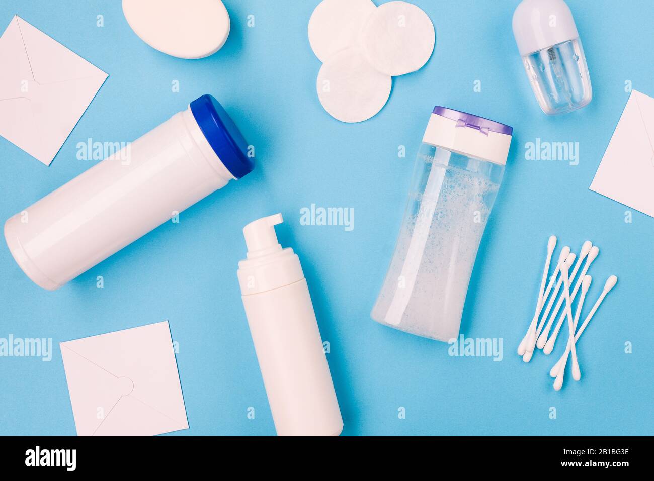 Cosmetic products on a blue background. Micellar water for makeup remover, foam, mask serum, dry perfume, soap and cotton buds. Flat lay, top view Stock Photo
