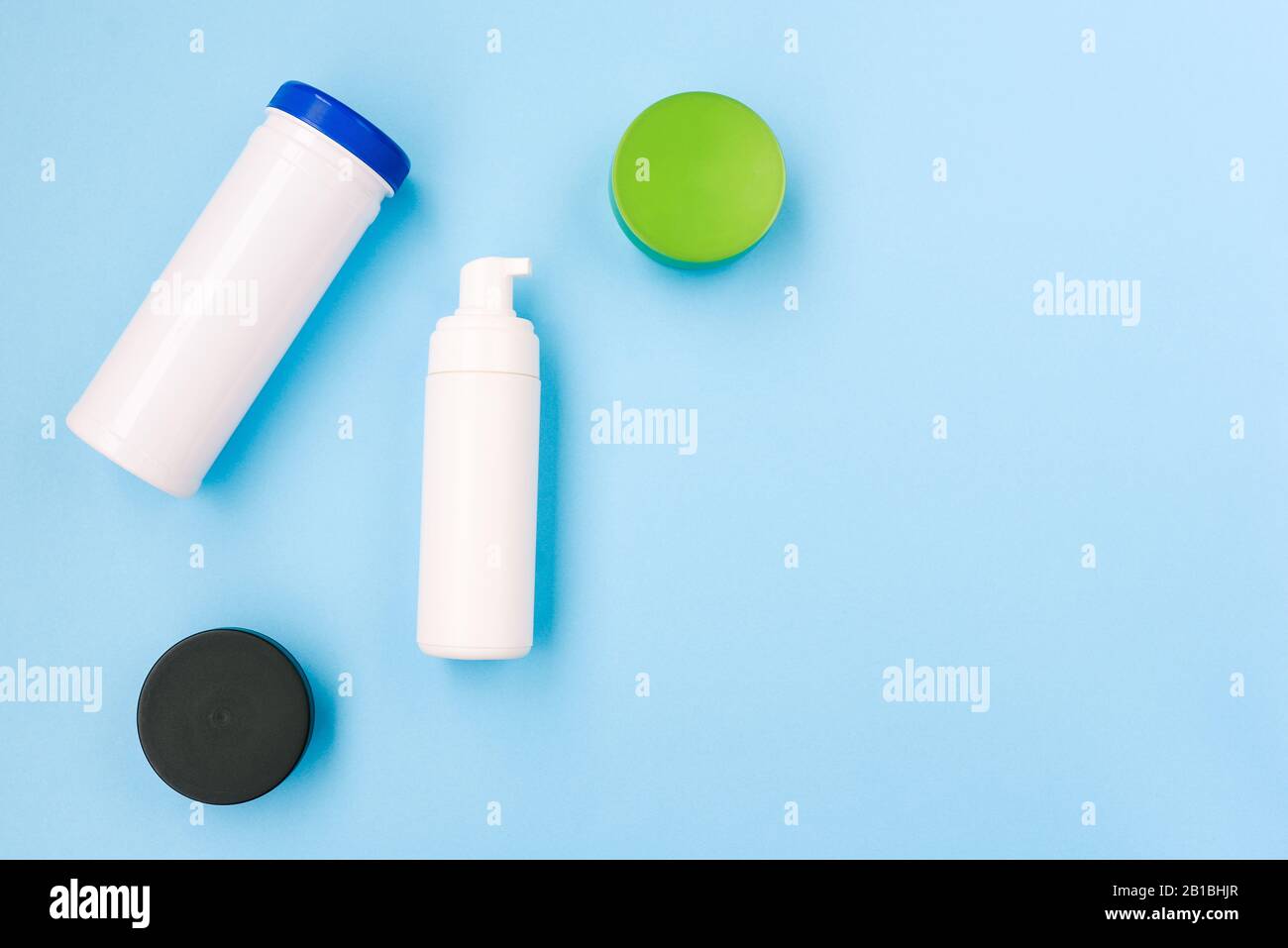 Female cosmetic products on a blue background. Green and black jar with cream. White can for wet wipes. Top view, copy space Stock Photo