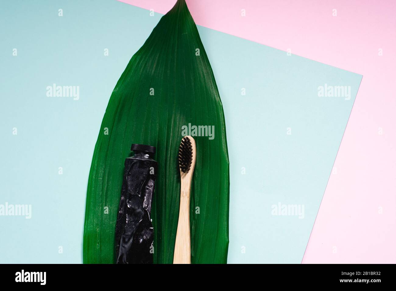 Bamboo wooden brush and toothpaste in a metal tube on a natural palm ...