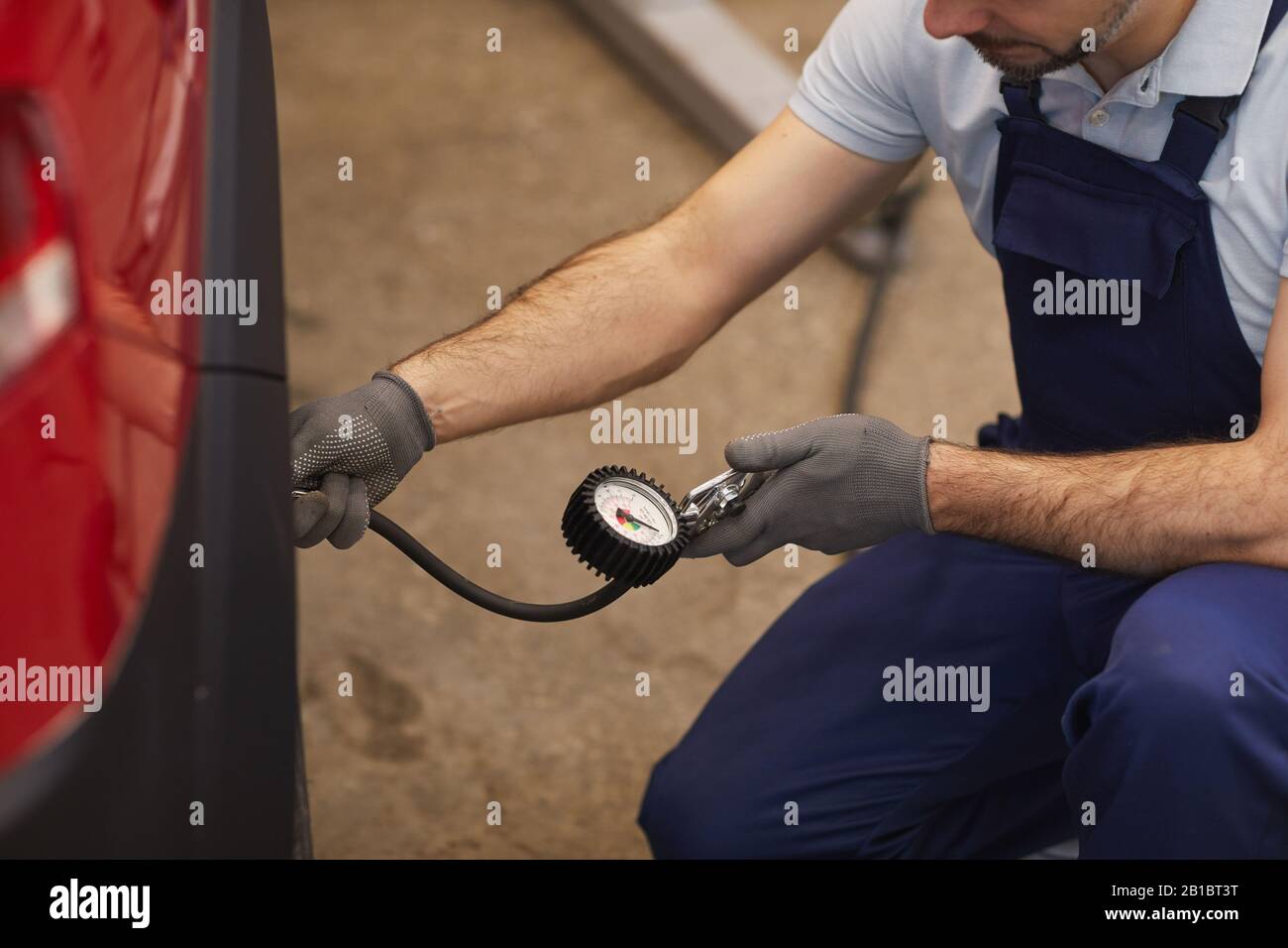 Close up of car mechanic checking pressure in tires during vehicle